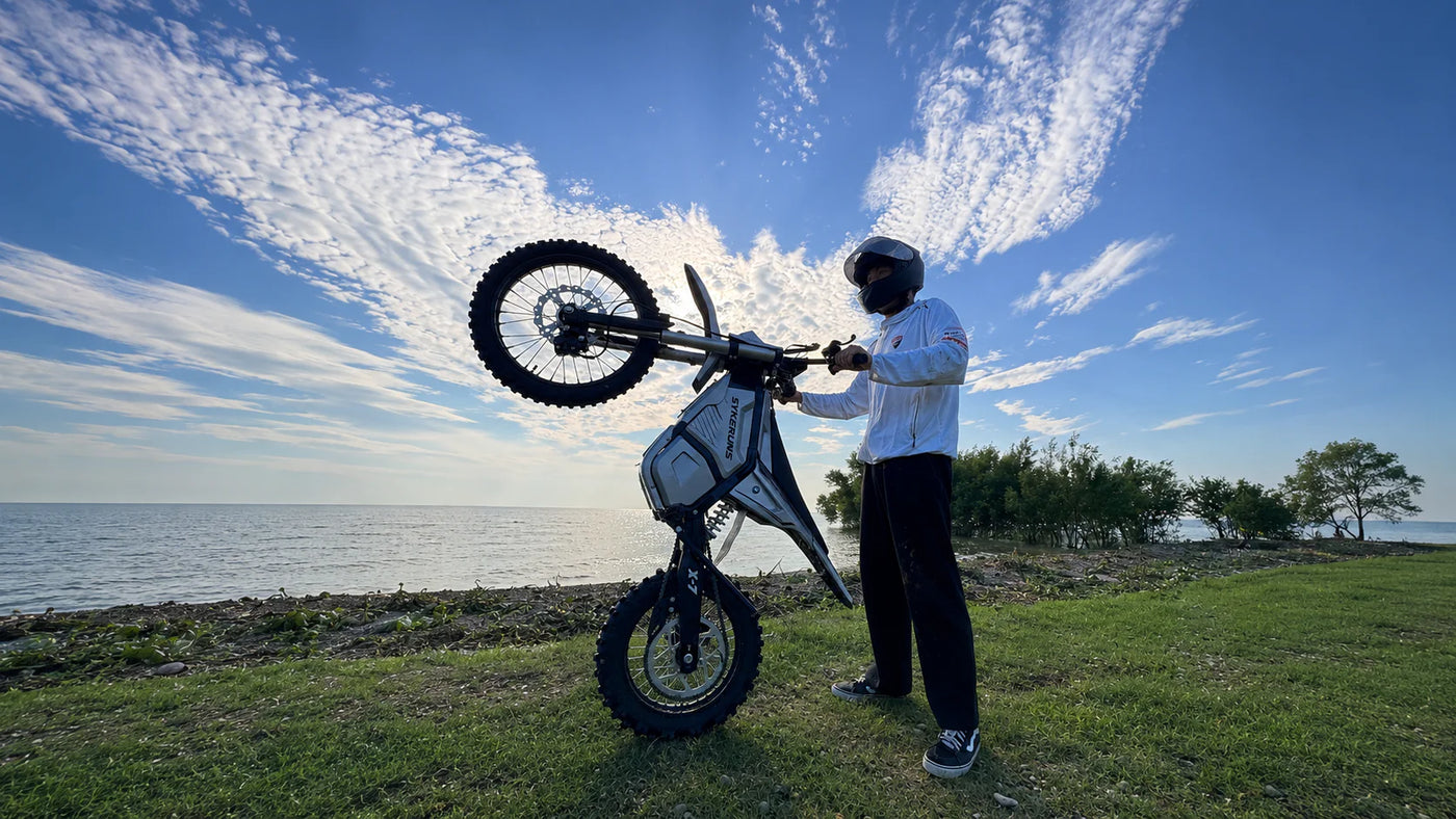 Adult rider demonstrating controlled front-wheel lift on a SYKERUNS X7 electric dirt bike