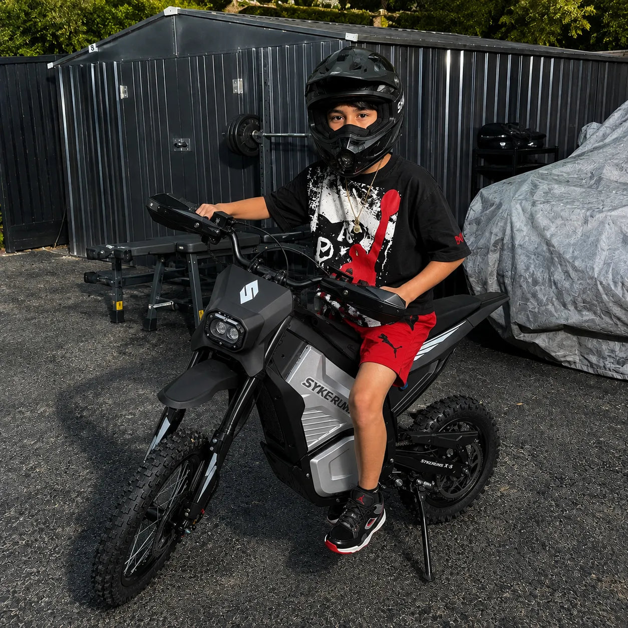 Rider on a SYKERUNS X5 electric dirt bike during an outdoor backyard ride