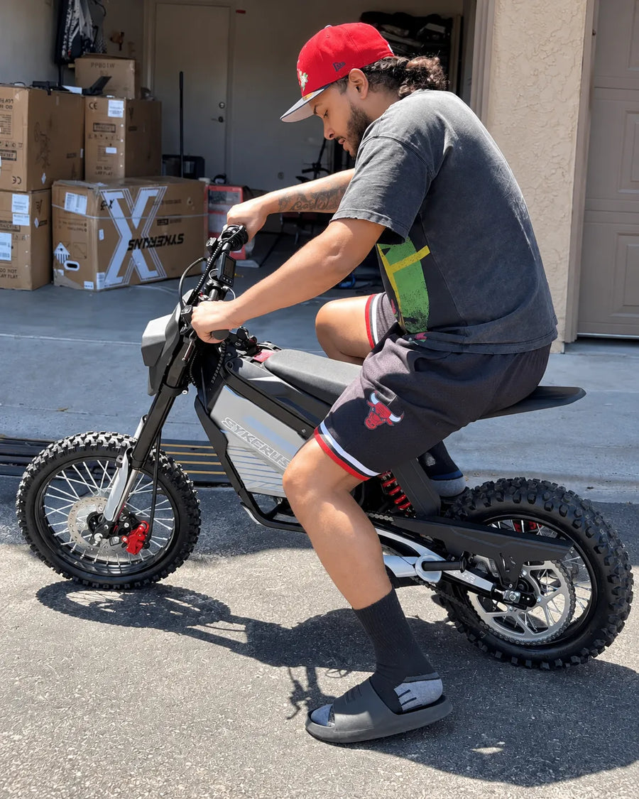 SYKERUNS X5 electric dirt bike rider outside a home garage