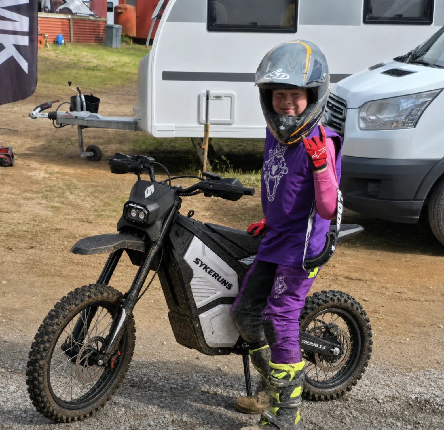 Off-road rider standing beside a SYKERUNS X5 electric dirt bike in riding gear