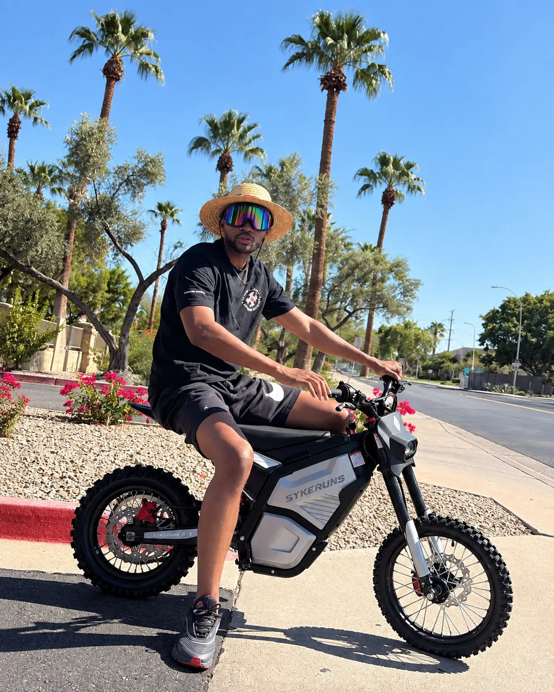 Real rider on a SYKERUNS X5 electric dirt bike outdoors under palm trees