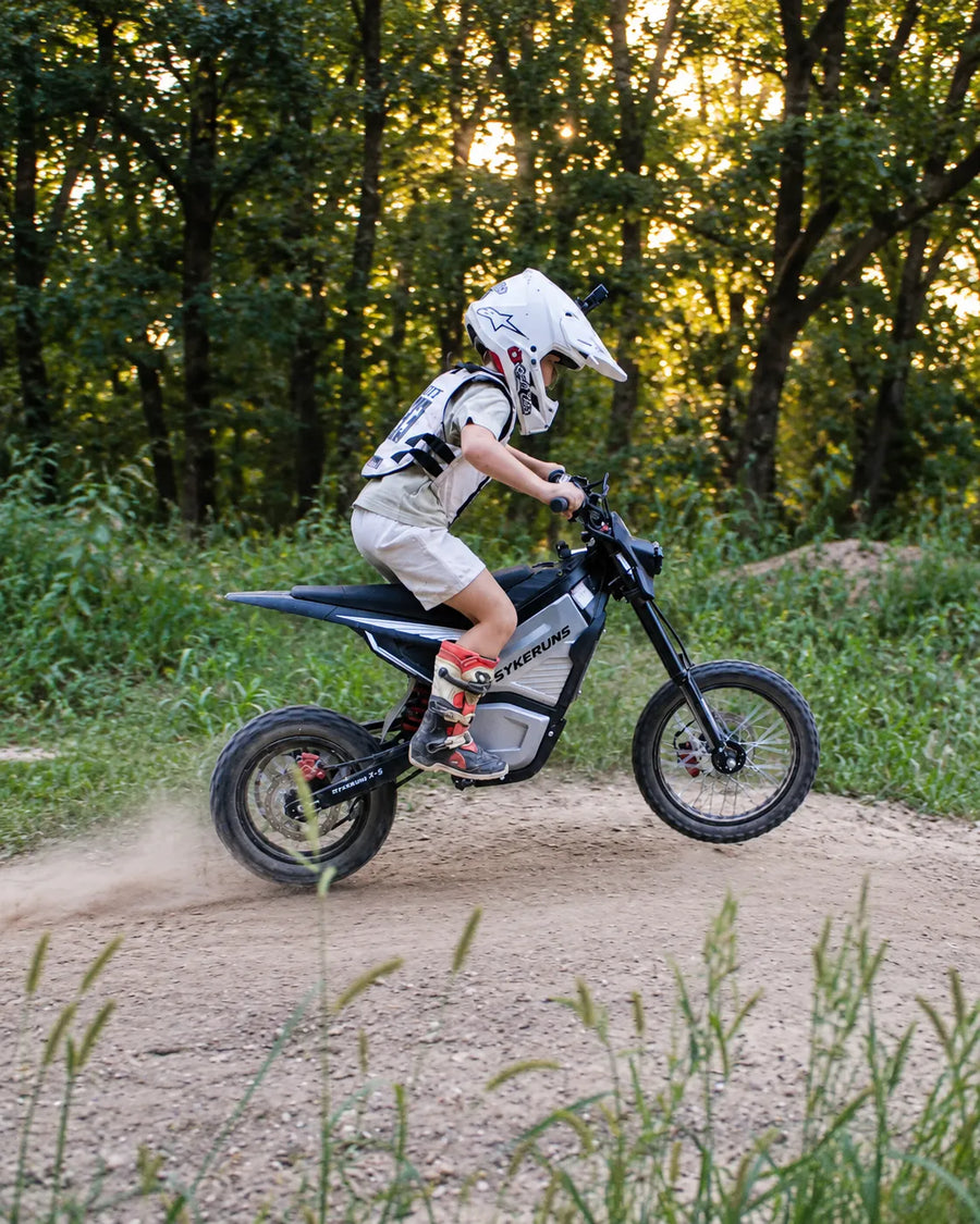 Helmeted rider riding a SYKERUNS X5 electric dirt bike on an off-road trail