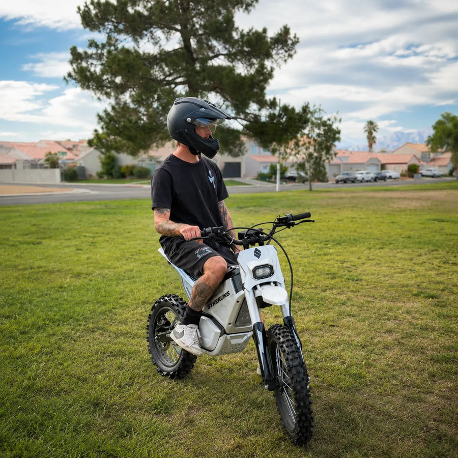 Real rider on a SYKERUNS X7 electric dirt bike in an outdoor grass field
